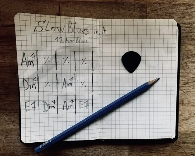 12 bar blues chord progression in A written in a notebook with pencil